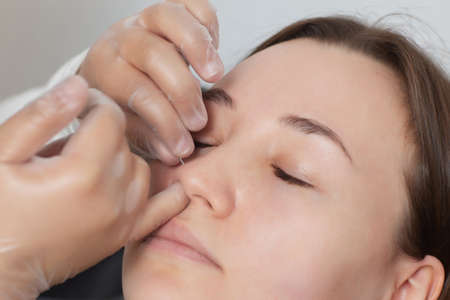 Closeup of a young womans visage with piercing hanging from her nose.の写真素材
