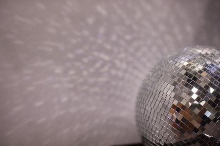 Shining disco ball on grey background close-up.