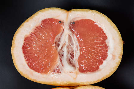 Half of grapefruit with vertical barbell piercing on a background.