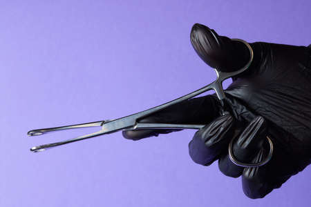 hand-held stainless steel surgical scissors with gloves.
