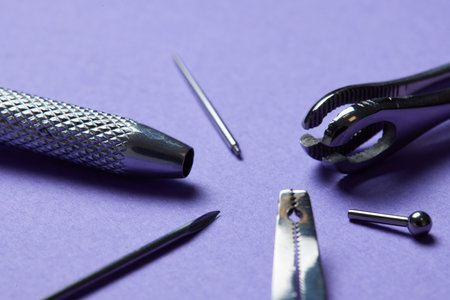 Piercing earrings close-up. On a Violet background.