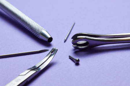 Piercing earrings close-up. On a Violet background.