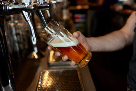 Pouring beer into a mug in a beer bar close-up. Beer bottling in the restaurant. The bar counter.の写真素材