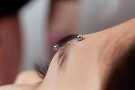 Professional placing the jewel of piercing on the temple on the head with ball. Tragus type.の写真素材
