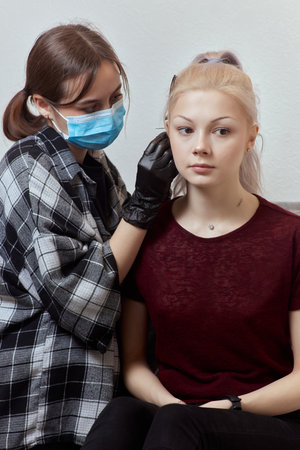 piercings on an ear. Conch and helix piercings close up. Professional holding the jewel.の写真素材