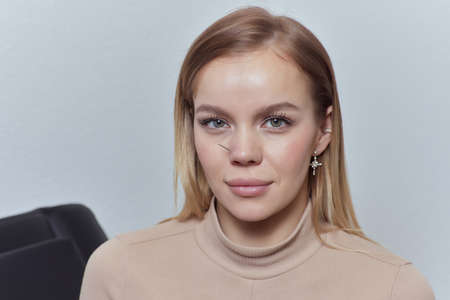 Closeup of a young womans visage with piercing hanging from her nose.
