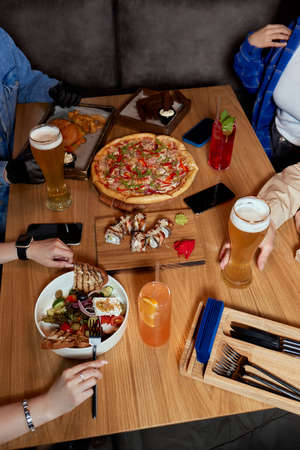 Enjoying dinner with friends. Top view of group of people having dinner together while sitting at the rustic wooden table.の写真素材