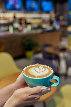 hand holding hot organic cocoa with foam froth art in black ceramic cup.の写真素材