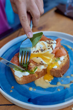 Young woman eat breakfast with knife and fork, Morning in cafe. Healthy breakfast with wholemeal...