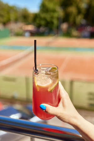 Young woman hands holding freshly squeezed strawberry lemonade of citrus fruits. Female with mason jar full of cold cocktail, lemon, orange, lime mint leaves.の写真素材
