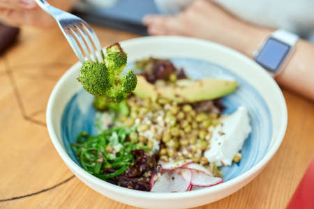 Woman eating quinoa broccoli salad. Eat healthy food lifestyle concept.の写真素材