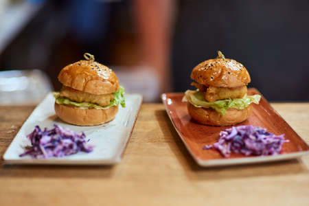 Tasty grilled beef burger with lettuce, ketchup, onion rings, chili and mayonnaise served on pieces...