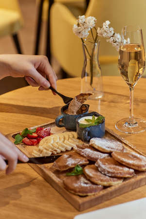 Female hands with forks and cake with berries on table with juice in cafe.の写真素材