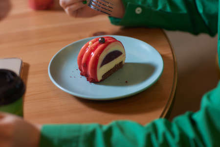 food, junk-food, culinary, baking and holidays concept - close up of woman eating chocolate cake with spoon and sitting at wooden table.の写真素材