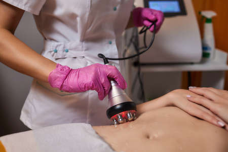 Rf skin tightening, belly. Hand of cosmetician, female body. Non surgical body sculpting.の写真素材