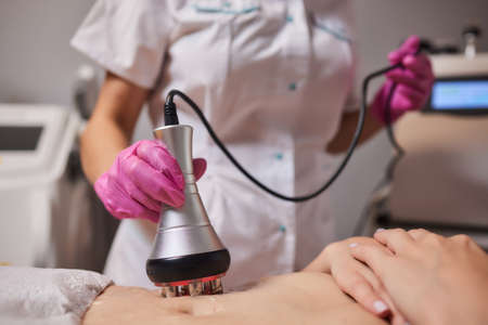 Rf skin tightening, belly. Hand of cosmetician, female body. Non surgical body sculpting.の写真素材