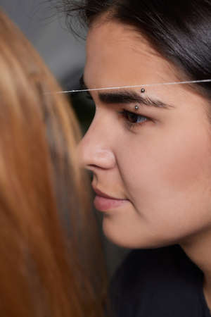 Beautiful young girl got correction of eyebrows in a beauty salon.の写真素材