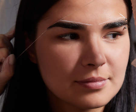 Beautiful young girl got correction of eyebrows in a beauty salon.の写真素材
