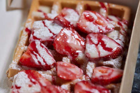 Freshly baked Belgian Liege Waffles sprinkled with powdered sugar with strawberries lying.の写真素材