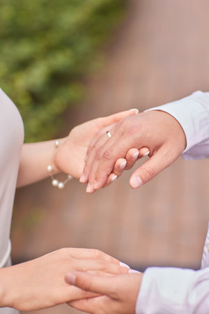 The groom is putting the wedding ring on the bride s finger. Close-up view of the hands.の写真素材