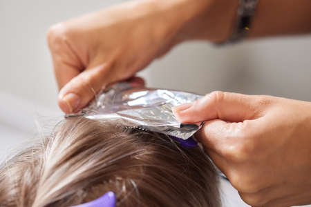 Hair stylist makes bouffant using comb on thin strands. Shatush technique for hair lightening.の写真素材