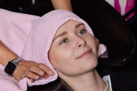 Beautiful hairstyle of young woman after dyeing hair and making highlights in hair salon.