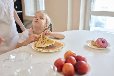 Little girl in the kitchen eats pancakes.の写真素材