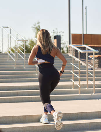 Athletic slim woman on a sunny day runs along the embankment or park.
