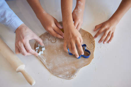 Close up picture of a young childs hand pressing a heart shape cookie cutter into soft rolled out dough to make sugar cookies.の写真素材