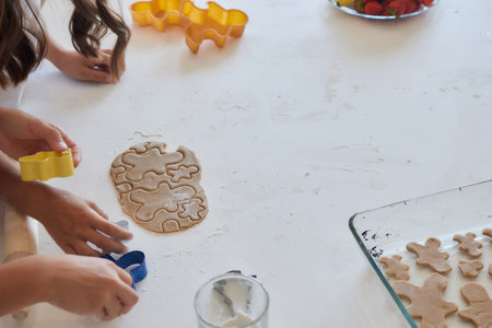 Close up picture of a young childs hand pressing a heart shape cookie cutter into soft rolled out dough to make sugar cookies.の写真素材