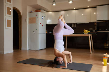 Beautiful young woman practicing yoga at home.