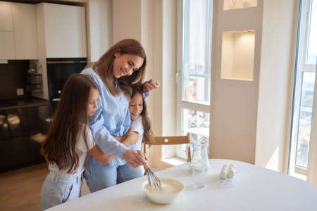 Cute kiss. Mother and daughter having good time in the kitchen.の写真素材