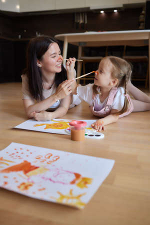 Little girl and their mother playing on warm floor with underfloor heating in living room. watercolor painting.の写真素材