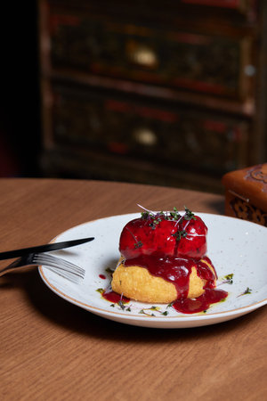 Pieces of roast duck meat lie on a white plate. Under the meat is a red sweet sauce. Decorated with...