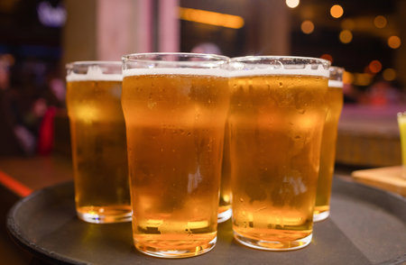 Waiter serving glasses of cold beer, on the tray.