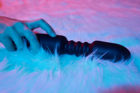 desire concept : Woman lying in bed holding a dildo vibrator in her hand to help herself.