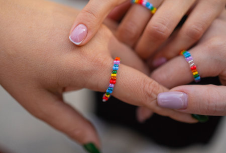 Crop of three girls showing her stylish manicure, holding their fingers on black leather handbag....