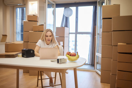 young blonde woman barcode printer and boxes on the background for market places.