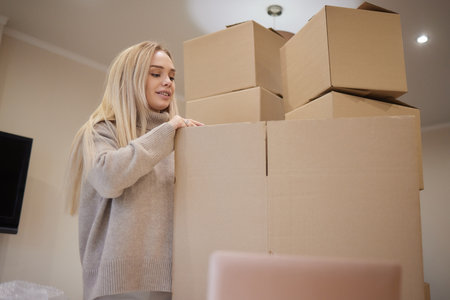Young happy American woman with stack of cardboard boxes.