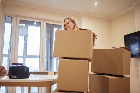 Young happy American woman with stack of cardboard boxes.
