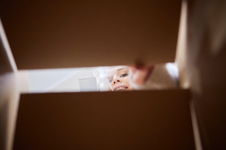 woman looking down at camera through cardboard box.