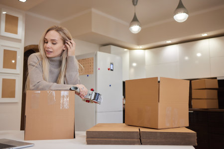 Young business woman taping up a cardboard box in the office, relocation and new business concept.の写真素材