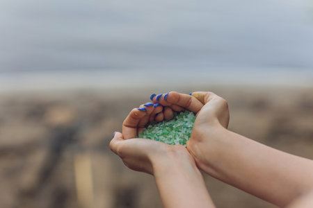 Tiny pieces of plastic collected from sandy beach in hands of environmentalist. Microplastic is polluting the sea and marine ecosystem.の写真素材