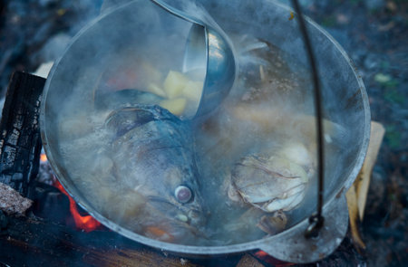 Cooking fish soup in the stowed bowler over a campfire.の写真素材