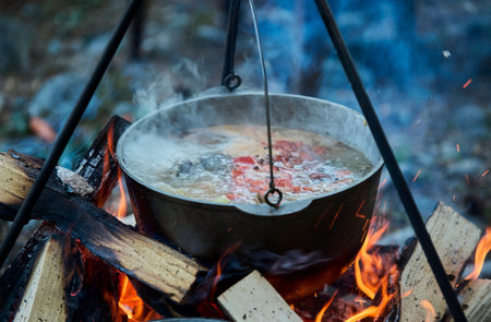 Cooking fish soup in the stowed bowler over a campfire.の写真素材
