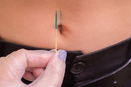 The first piercing. Dressing the earrings on the navel. Female piercing.の写真素材