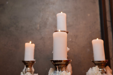 Light candle in the brass candlestick closeup on a dark background.の写真素材