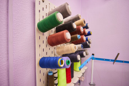 Set of various colorful threads placed on organizer in light workshop during daytime.