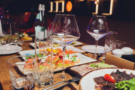Served for holiday banquet restaurant table with dishes, snack, cutlery, wine and water glasses. European food.の写真素材