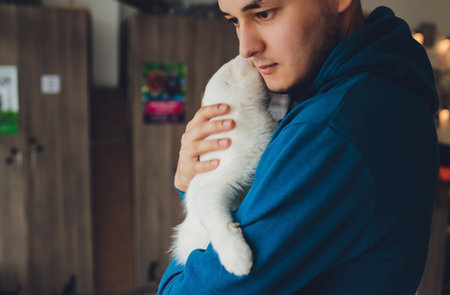 young man holding a white cat close-up.の写真素材